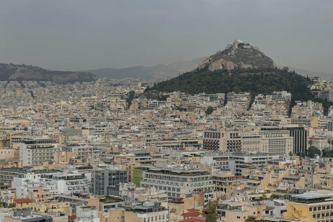 Wide view over Athens toward mountains — ATH airport, Piraeus port, and city transfers